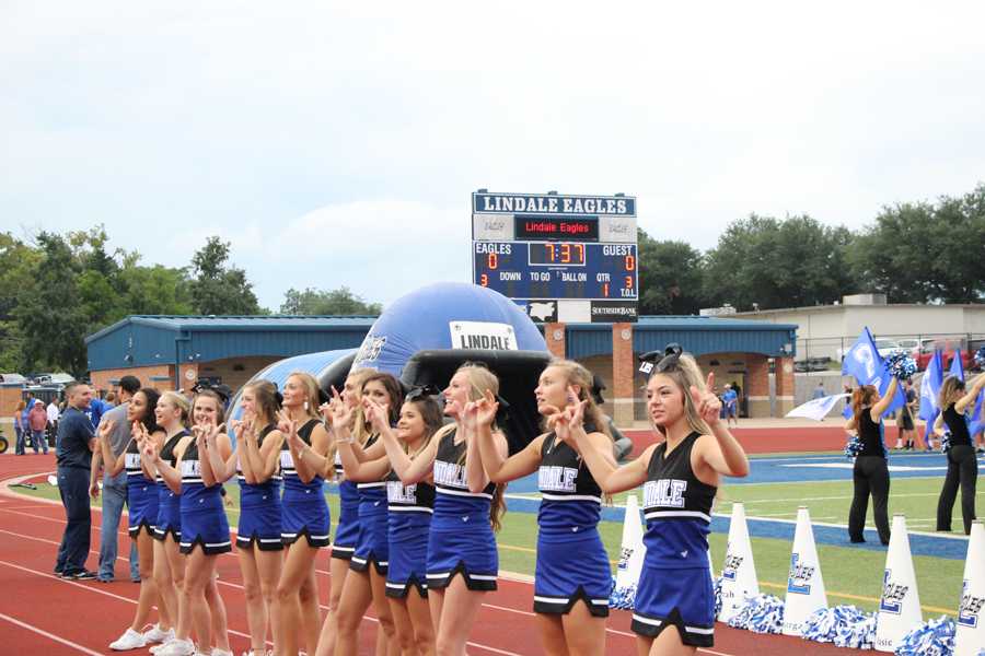 Cheerleaders lock hands on the sidelines before the start of a game.