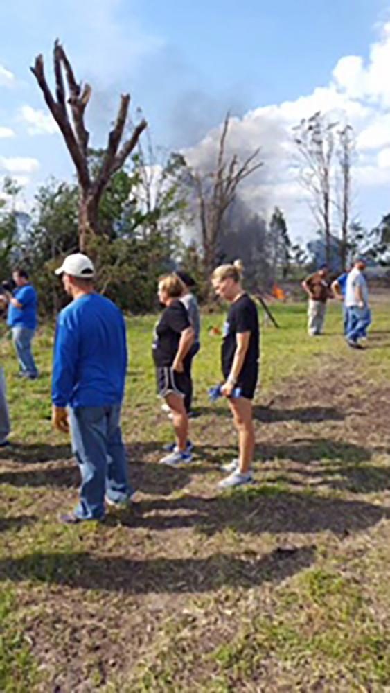 Coaches assist the students in picking up debris. They cleaned up most of the yard in only a few hours.