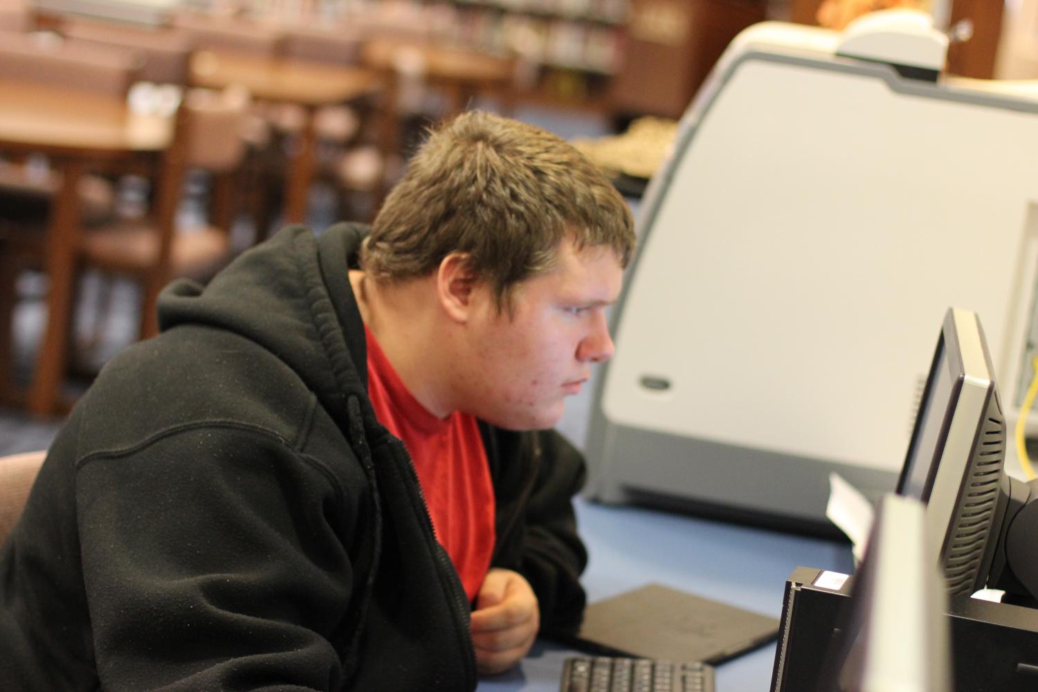Student Technician James Appl works on a computer in the library. Appl is currently the only student technician in the school.