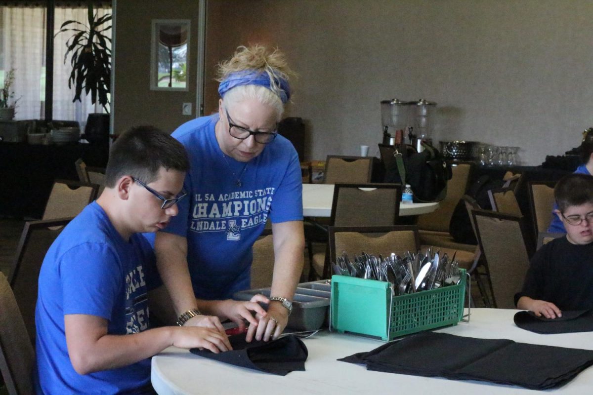 Students roll silverware at the Hideaway Lake Clubhouse.  After all of their hard work each Friday, they receive a free soda. 