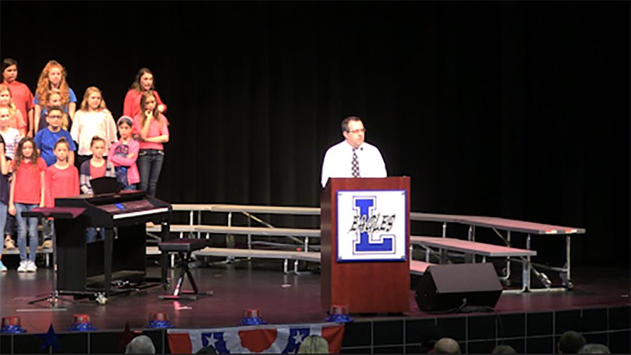 Choir instructor Casey Halbgewachs speaks at  the Veteran Day assembly. EJ Moss students performed God Bless America along with other patriotic songs to honor veterans.