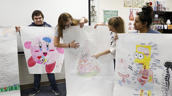 Students show off their character anatomy posters. They hung them in the hallway outside of the classroom. 