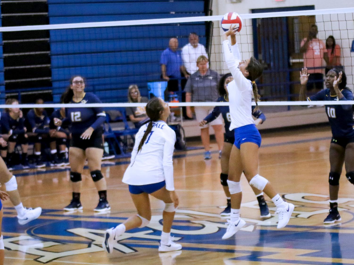 Junior Harleigh Thurman sets the ball as fellow junior London Reue prepares to spike it down. The varsity team beat Pine Tree in straight sets with scores of 25-23, 25-14, and 25-14.                                                                                                                                                                                                                                                                    