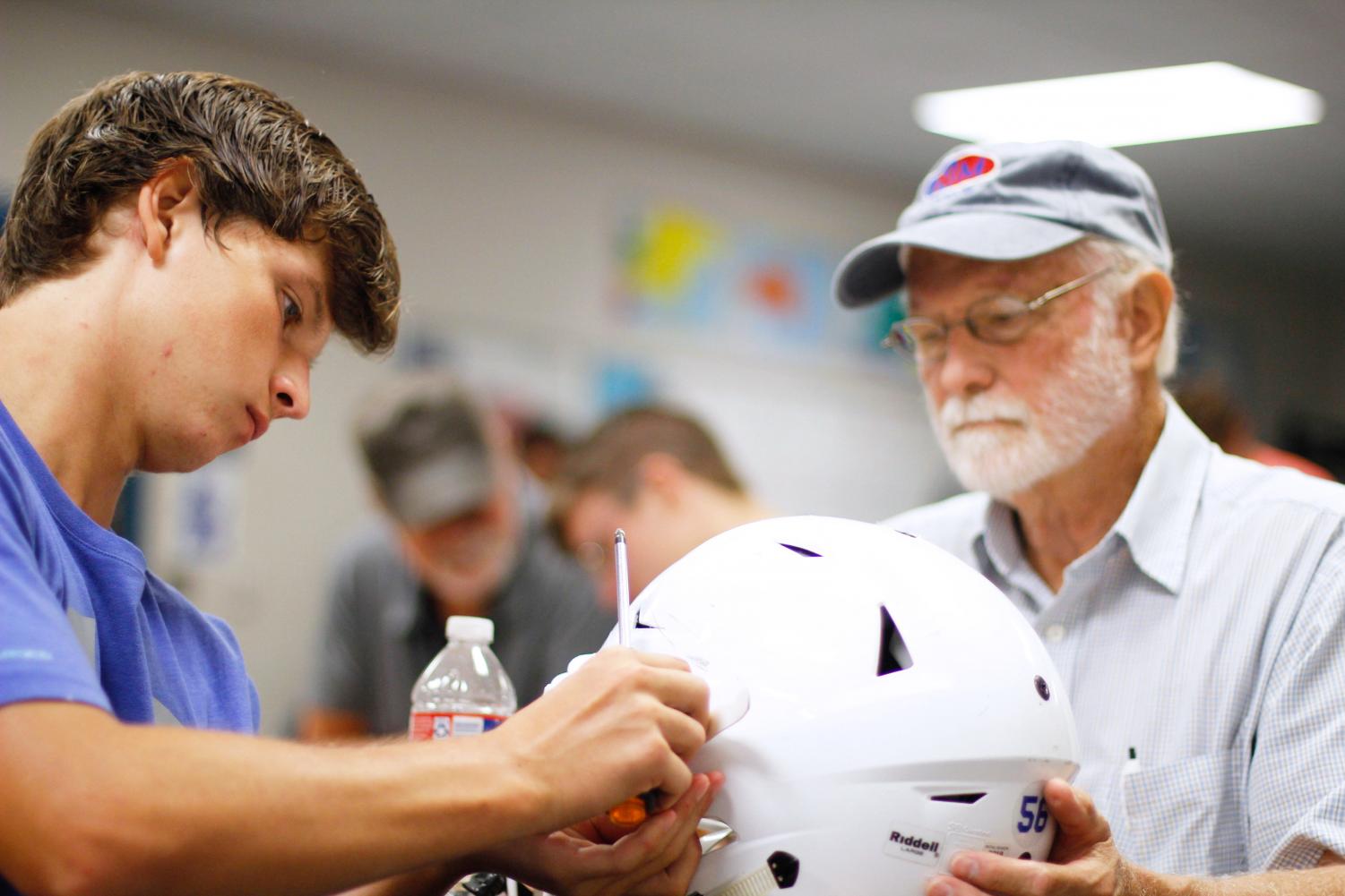 Senior Copeland Taylor and his grandfather place the EAGLES decal on his helmet. This event was started last year as a way to strengthen bonds with the community.