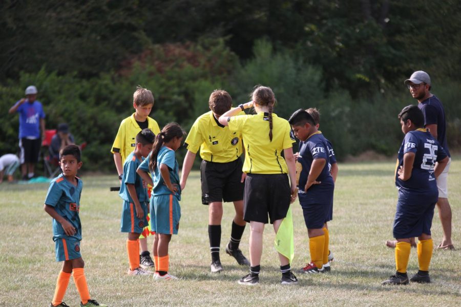 Senior Colleen Starkey, eighth grader Otto Straus and seventh grader Seth Derksen perform a coin toss at a tournament game. Many referees for youth games like this have quit due to unruly parents or coaches.