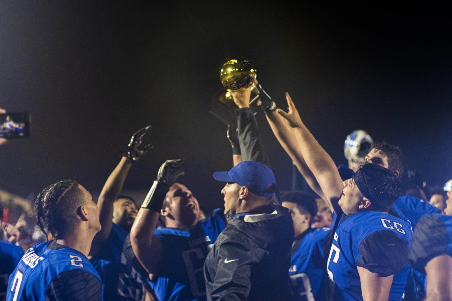 Head coach Chris Cochran holds the golden football trophy with the team. The Eagles won against Austin LBJ in the semifinal game with a score of 31-28.