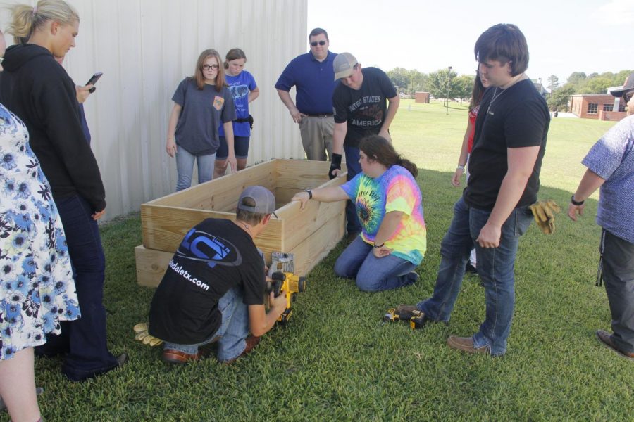 FFA students work together to build a planter bed in front of the library.