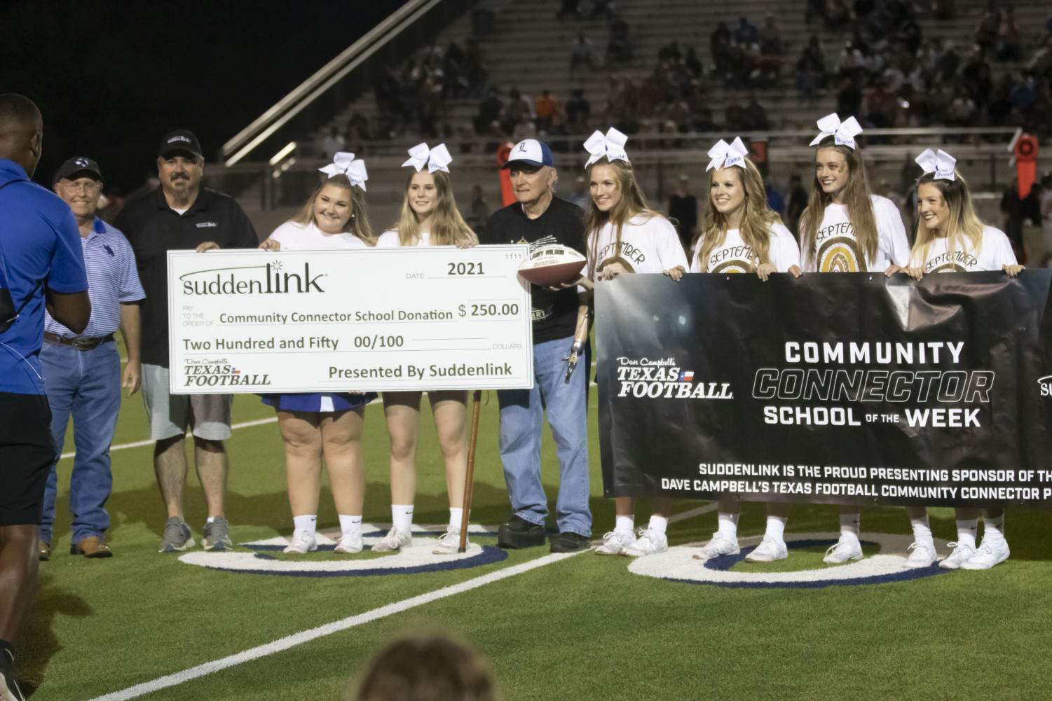 Community leader Larry Wilson poses with the cheerleaders as he accepts his award. Wilson received his award after first quarter during the football game on Sept. 17.
