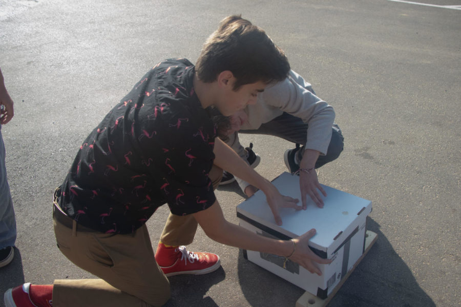Seniors Tyler Chamberlain and Chris Tate prepare their camera to take a picture in the parking lot. The camera was made from cardboard and tape. 