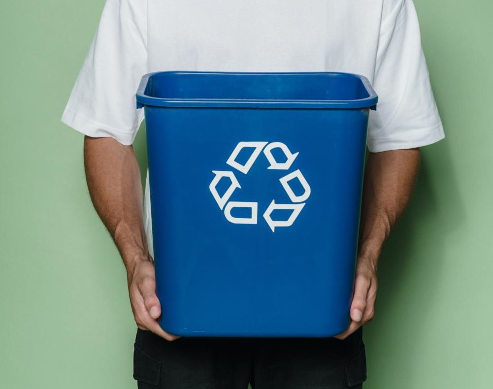 A man holds a recycling bin. FFAs bins will look similar to this.