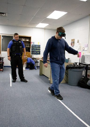 Officer Dewolfe allows students to test impairment goggles.