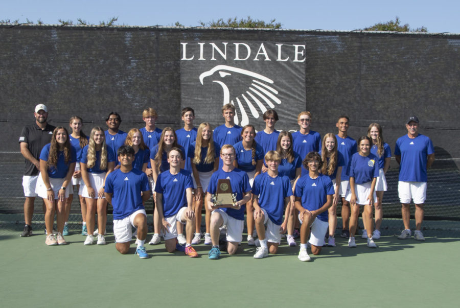 Tennis team poses after winning a game. The team is undefeated in 4A.