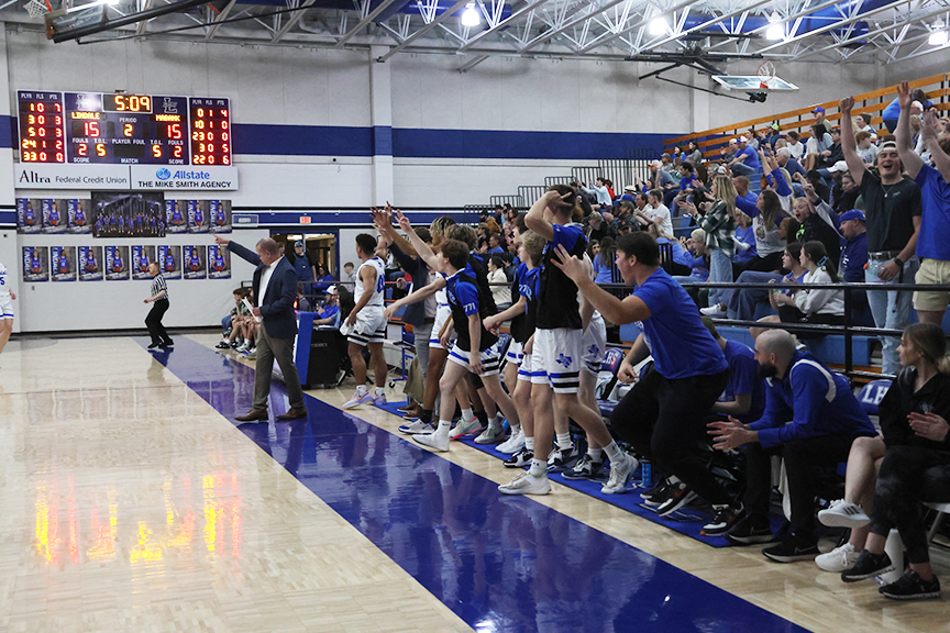 The varsity boys basketball team cheers as their team scores a point. They won against Mabank 48-39