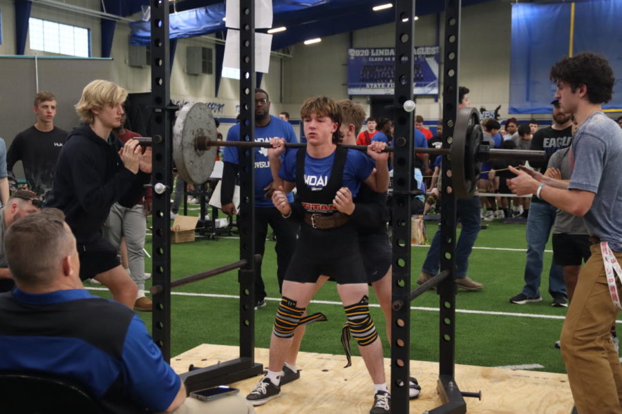 Powerlifting members compete at a home meet.
