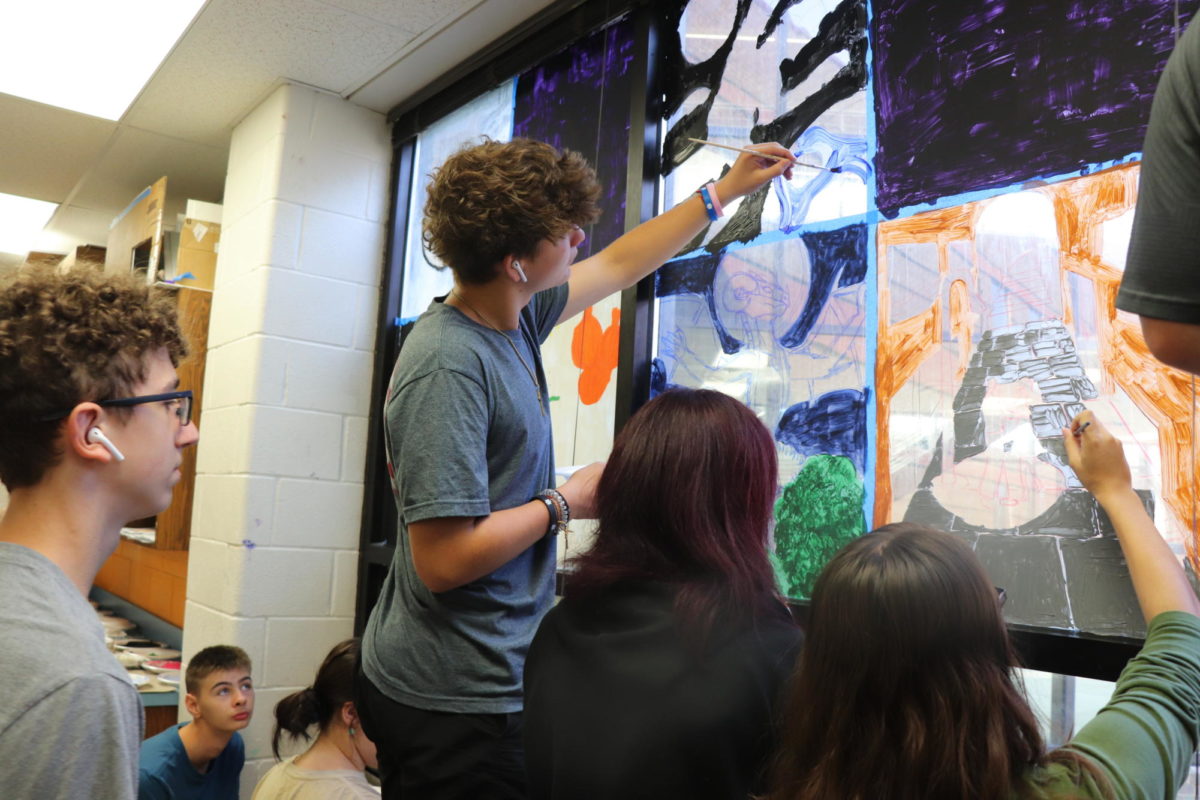 Sophomore Christopher Dworaczyk paints art mural on window. 