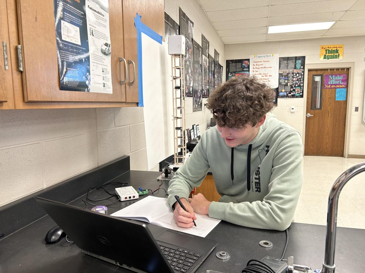 Senior Kaden Strickland records data from the experiment. The class has been working on the buildings for three to four weeks.