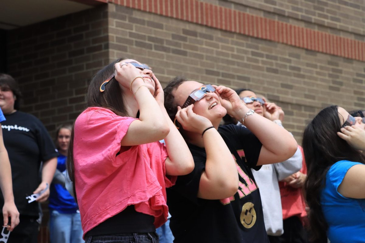 Junior Sydney Hines and Madi Gasser look out at the solar eclipse right before it reaches totality.