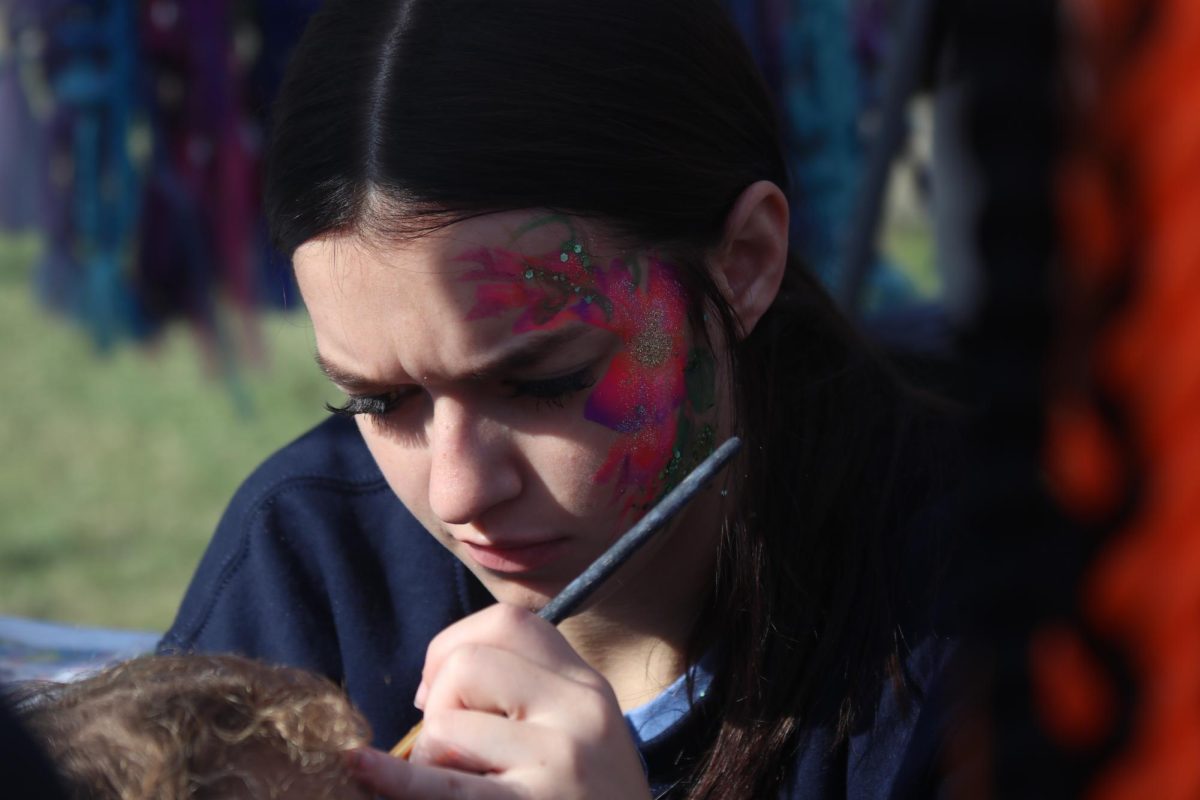 Junior Faith Olds volunteers for face painting at the country fest. The booth also had colorful hair extensions. 