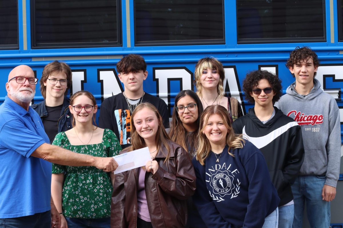 Isabelle Stanford hands the $800 check to a faculty member of the David Powell Community Food Pantry. "I chose to participate in the Empty Bowls event because I wanted to use my skills to give back to our community," Stanford said. "I enjoy being able to help others and this seemed like a great way to do so."